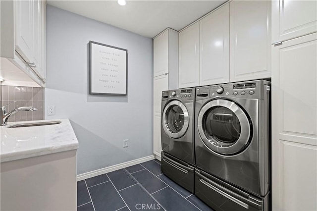 laundry room with baseboards, washer and clothes dryer, dark tile patterned floors, cabinet space, and a sink