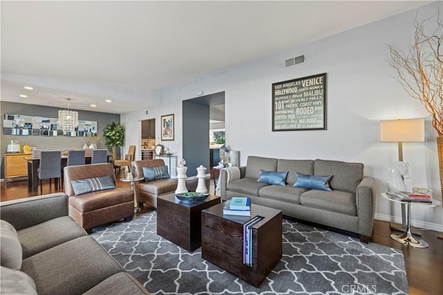 living room with visible vents, baseboards, recessed lighting, an inviting chandelier, and wood finished floors