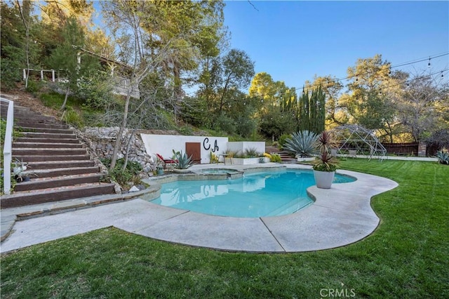 view of swimming pool with stairs, a pool with connected hot tub, a lawn, and a fenced backyard