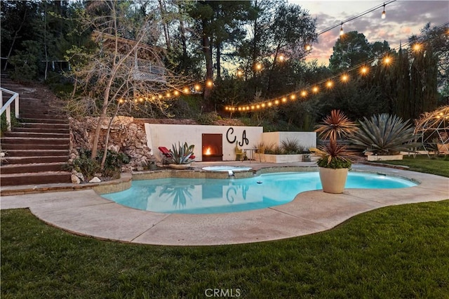 pool at dusk with stairway and a pool with connected hot tub