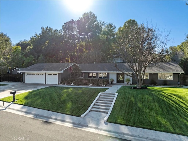 ranch-style home featuring an attached garage, concrete driveway, and a front lawn