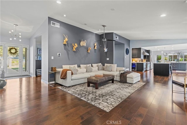 living room with dark wood finished floors, lofted ceiling, visible vents, and a chandelier