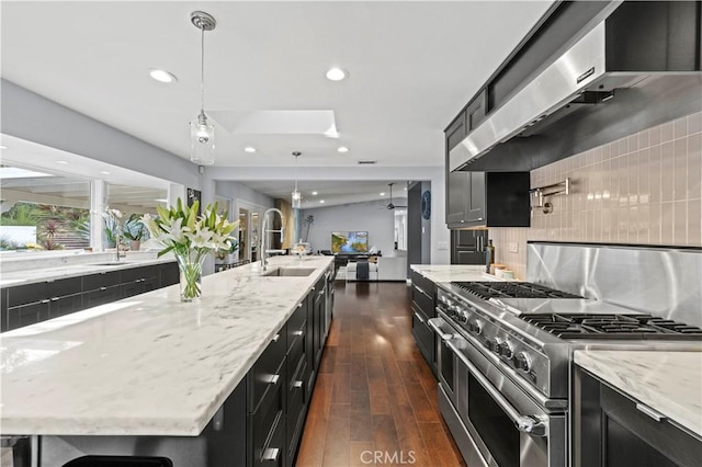 kitchen with double oven range, a sink, decorative backsplash, extractor fan, and dark cabinets