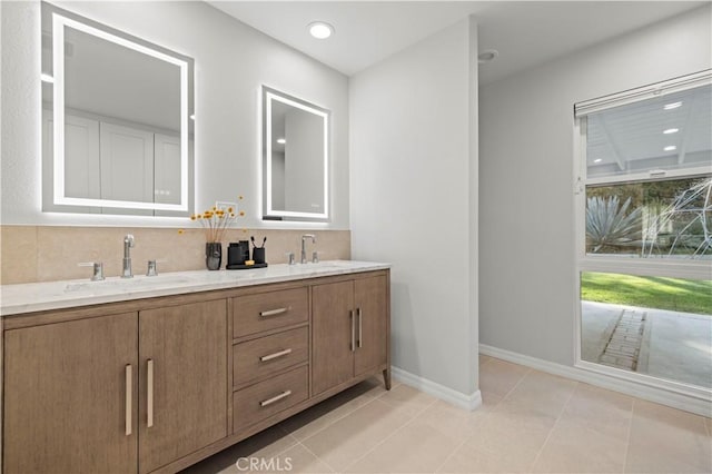 full bathroom with double vanity, tile patterned floors, baseboards, and a sink