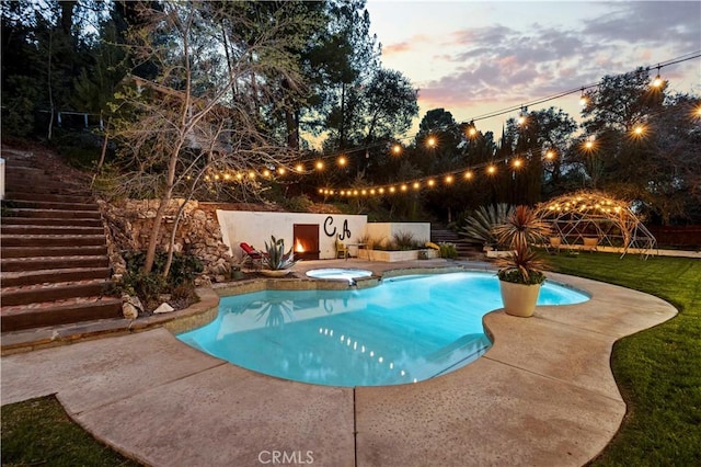 pool at dusk with an in ground hot tub, a patio area, and an outdoor pool