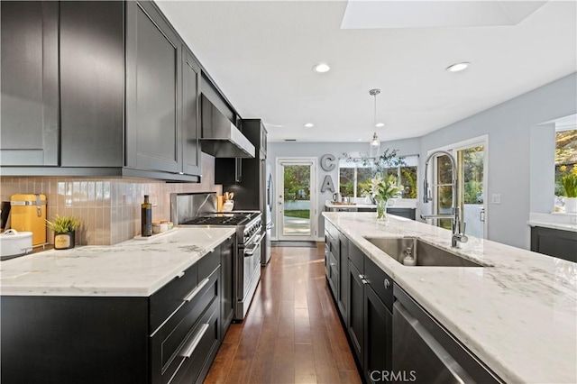 kitchen featuring tasteful backsplash, a sink, light stone countertops, stainless steel appliances, and dark cabinets