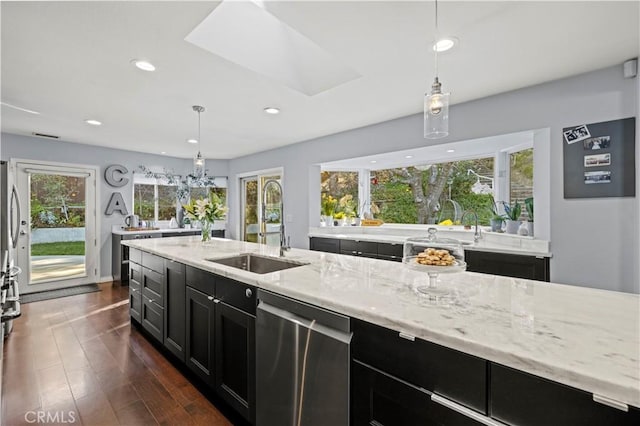 kitchen featuring dark cabinets, light stone counters, stainless steel dishwasher, dark wood-style floors, and a sink