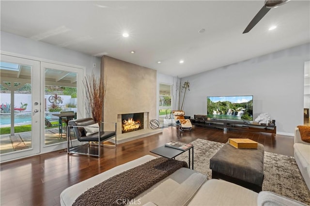 living room featuring a large fireplace, plenty of natural light, and wood finished floors