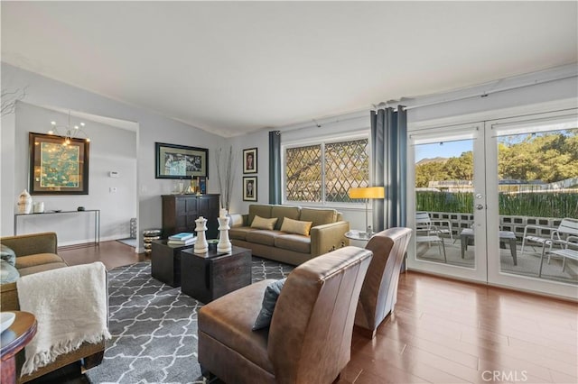 living area featuring a chandelier, wood finished floors, and vaulted ceiling