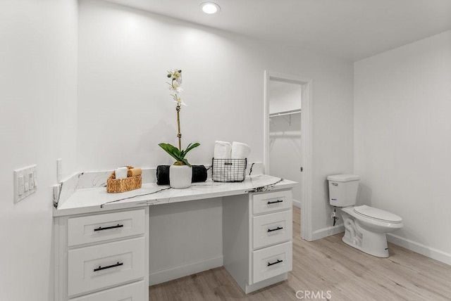 bathroom with vanity, toilet, wood finished floors, and baseboards