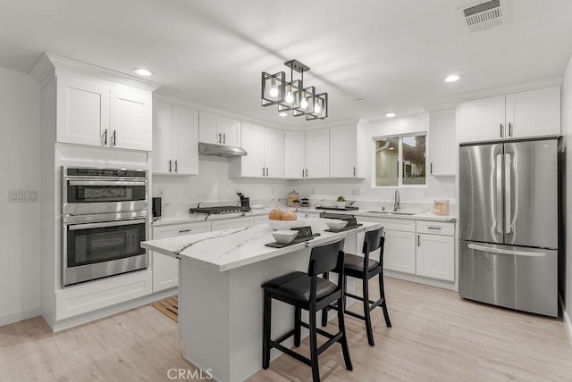 kitchen featuring under cabinet range hood, appliances with stainless steel finishes, white cabinetry, and a sink