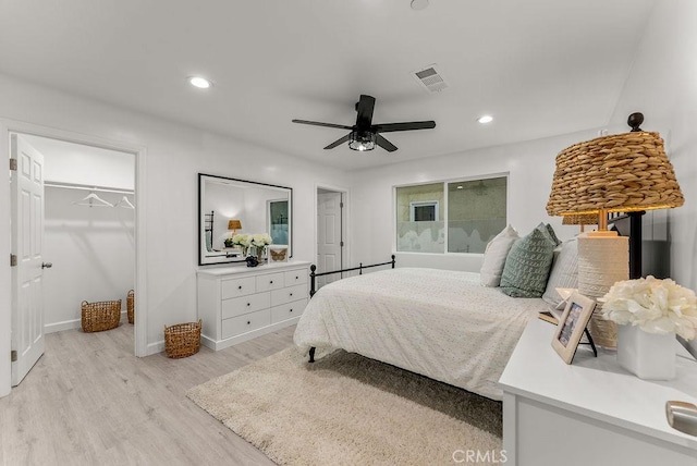 bedroom with visible vents, light wood finished floors, recessed lighting, ceiling fan, and a walk in closet