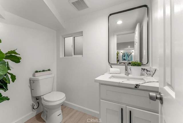 bathroom with visible vents, toilet, wood finished floors, baseboards, and vanity