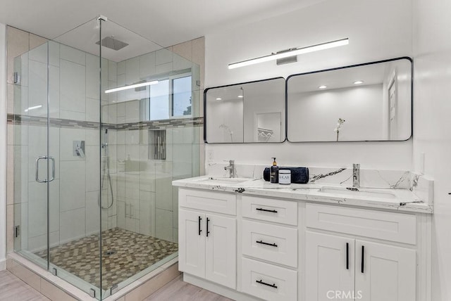 full bath with double vanity, a stall shower, and a sink