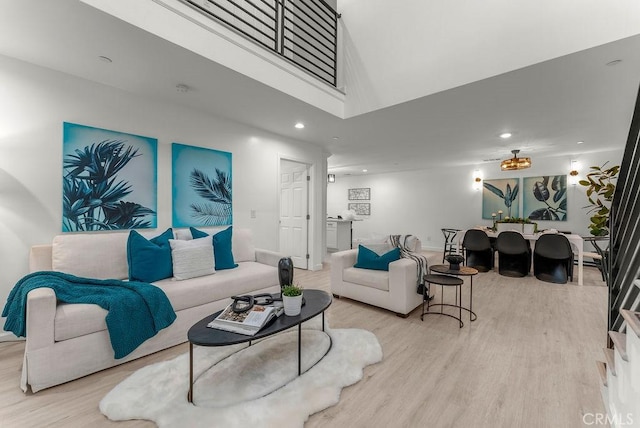 living room with recessed lighting, wood finished floors, and a towering ceiling