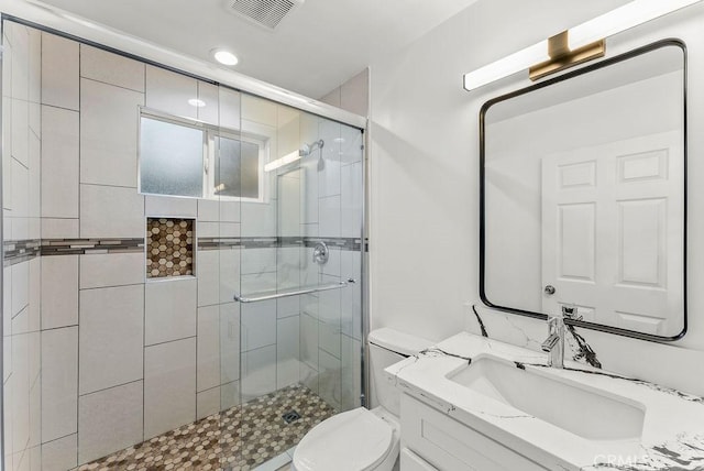 full bathroom with visible vents, toilet, a stall shower, and vanity