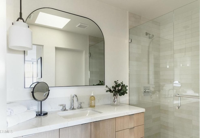 bathroom featuring vanity, a shower stall, a skylight, and visible vents