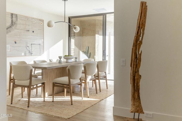 dining area featuring a wealth of natural light, floor to ceiling windows, and wood finished floors