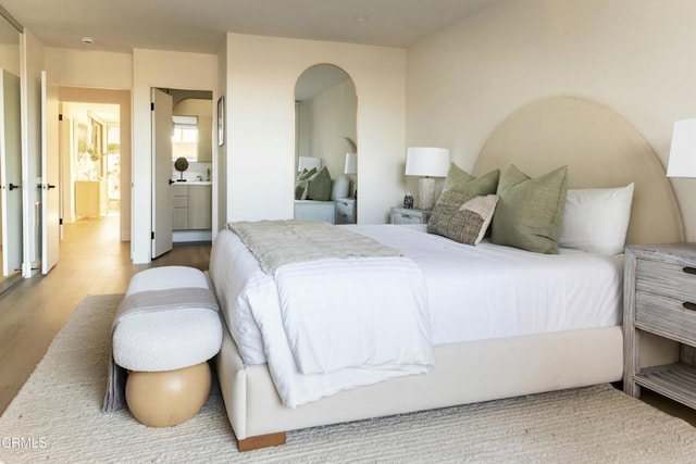 bedroom featuring ensuite bath and wood finished floors