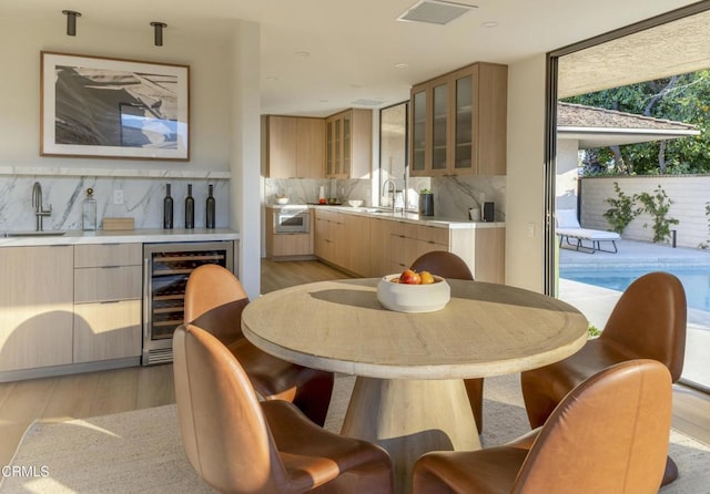 dining area with visible vents, light wood-style flooring, wine cooler, a wall of windows, and wet bar