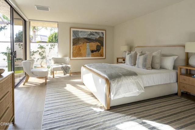 bedroom featuring visible vents, wood finished floors, and expansive windows