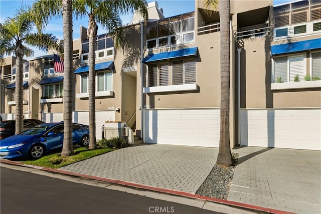 view of property with a garage and decorative driveway