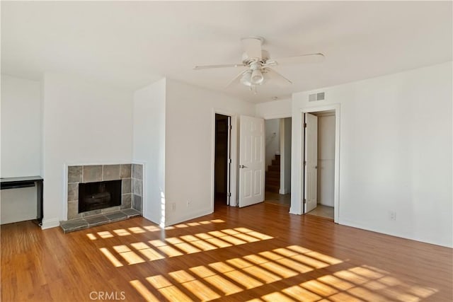 16061 Surprise Ln, Huntington Beach, CA 92649 - unfurnished living room featuring visible vents, a fireplace with raised hearth, ceiling fan, baseboards, and wood finished floors