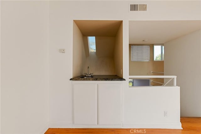 16061 Surprise Ln, Huntington Beach, CA 92649 - kitchen featuring visible vents, a sink, dark countertops, white cabinets, and light wood finished floors