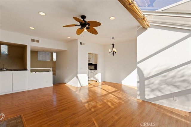 16061 Surprise Ln, Huntington Beach, CA 92649 - unfurnished living room with ceiling fan with notable chandelier, recessed lighting, wood finished floors, and visible vents