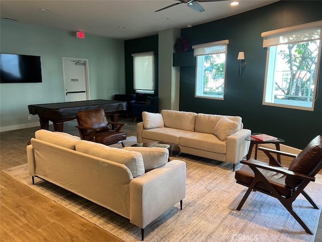 living room featuring baseboards, recessed lighting, a wood stove, wood finished floors, and a ceiling fan