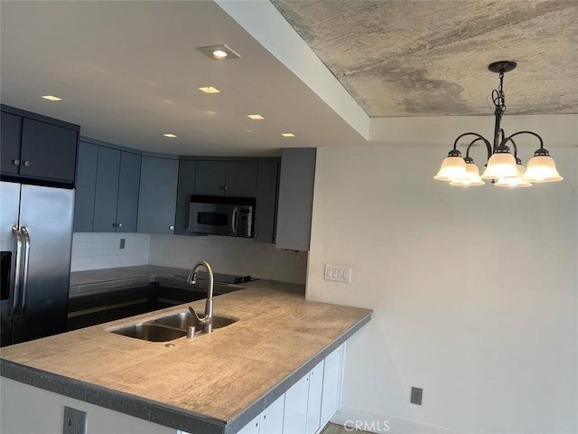 kitchen with backsplash, decorative light fixtures, a peninsula, stainless steel appliances, and a sink