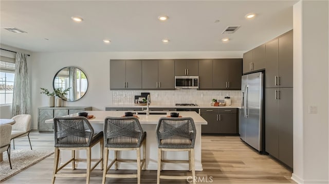 kitchen with stainless steel appliances, visible vents, a breakfast bar area, and light countertops