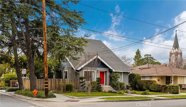 view of front facade featuring fence and roof with shingles