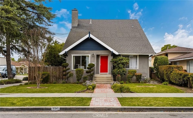 bungalow featuring a chimney, a shingled roof, a front yard, and fence