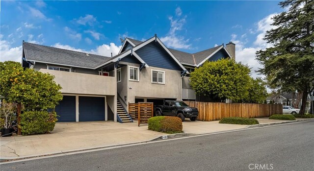 view of front of house featuring fence, stucco siding, stairs, concrete driveway, and a garage