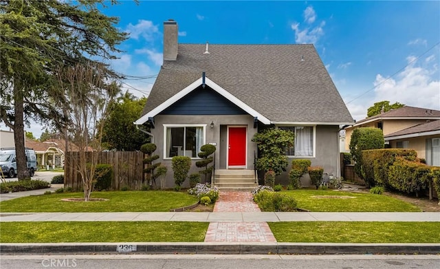 bungalow with roof with shingles, a chimney, a front lawn, and fence