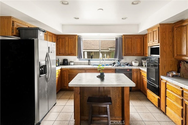 kitchen with light tile patterned floors, stainless steel appliances, tile counters, and a sink