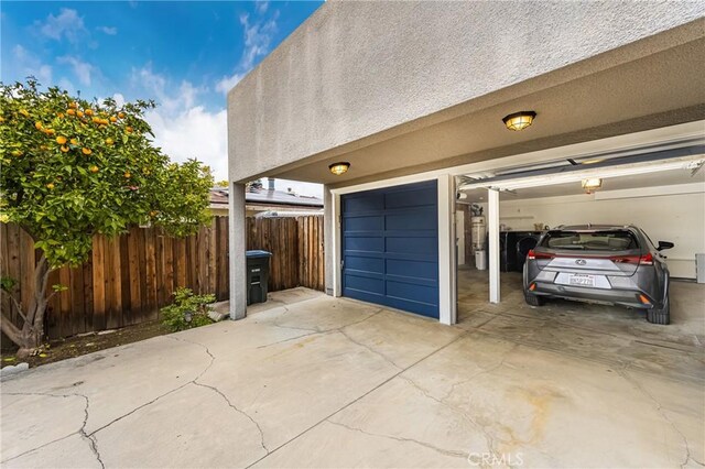 garage featuring concrete driveway and fence