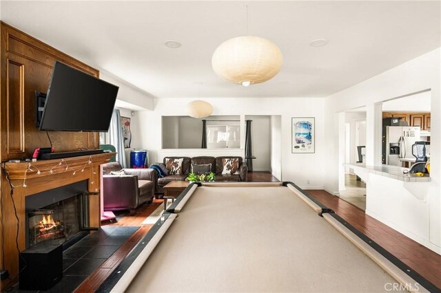 recreation room with a tiled fireplace, pool table, and wood finished floors