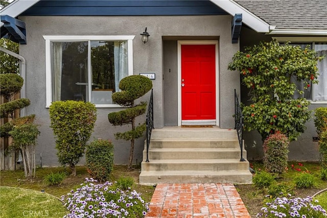 property entrance featuring stucco siding and roof with shingles