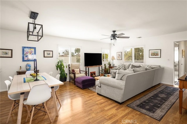 living area with ceiling fan, light wood-type flooring, and baseboards