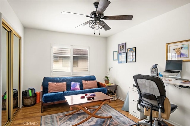 office area with light wood-style floors, baseboards, and ceiling fan