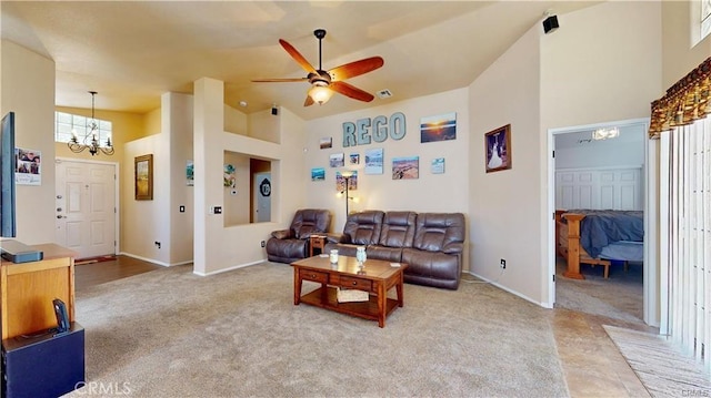 living room with visible vents, baseboards, a towering ceiling, ceiling fan with notable chandelier, and light colored carpet