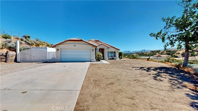 view of front facade with stucco siding, driveway, a gate, fence, and a garage