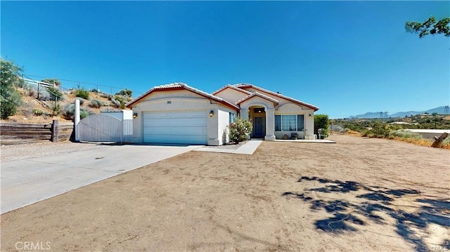 view of front of property featuring a gate, fence, driveway, stucco siding, and a garage