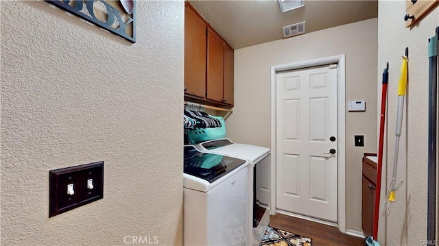 washroom featuring independent washer and dryer, cabinet space, dark wood-style floors, and visible vents