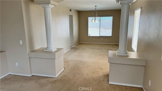 unfurnished living room with decorative columns, visible vents, and light carpet