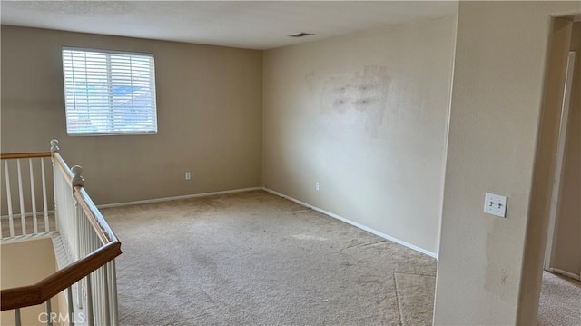 unfurnished room featuring carpet flooring, visible vents, and baseboards