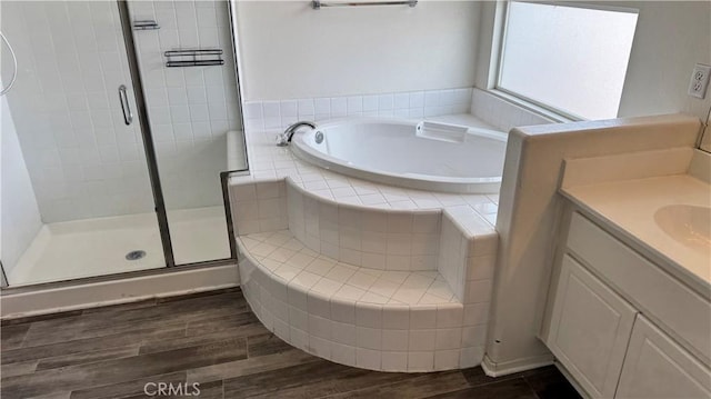 full bathroom featuring a shower stall, vanity, a garden tub, and wood finished floors