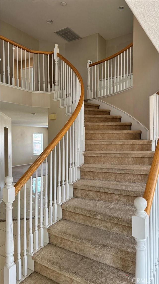 stairway featuring visible vents and a high ceiling